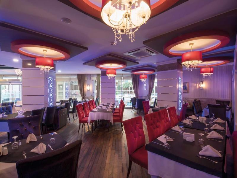 Elegant restaurant with round ceiling lights, red chairs, and neatly set tables.