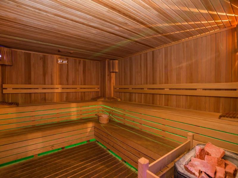 Cozy wooden sauna with tiered benches and warm lighting, featuring a heater with stones.