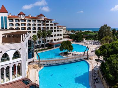 Hotel di lusso con grandi piscine e vista mare, circondato da palme e terrazze soleggiate.