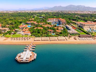 Langer Sandstrand mit Sonnenschirmen, Hotels und grünen Bäumen entlang der Küste.