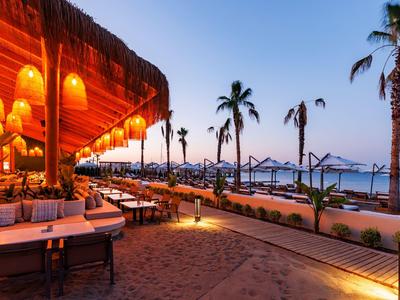 Restauracja przy plaży o zachodzie słońca z palmami i relaksującą atmosferą.