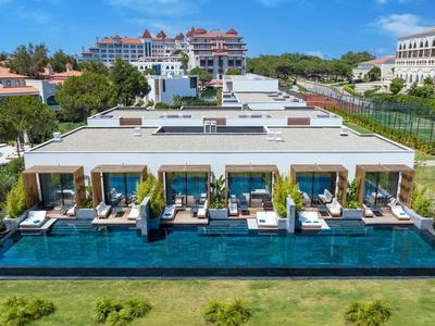 Luxuriöse Villen mit privatem Pool, Liegestühlen und Blick auf grüne Gärten unter blauem Himmel.
