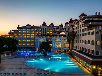 Luksusowy hotel z oświetlonym basenem o zachodzie słońca w tropikalnym otoczeniu