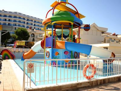 Bunter Wasserspielplatz mit Rutschen und Fontänen in einem Pool vor einem Hotelgebäude.