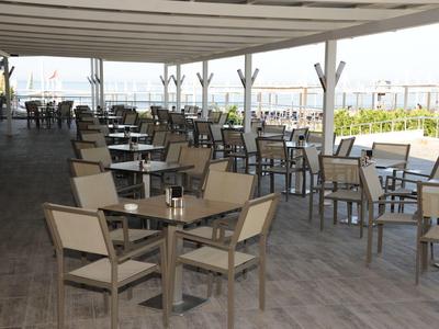 Leerer Außenbereich eines Cafés mit vielen Stühlen und Tischen unter einem großen Sonnendach.