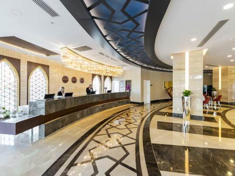 Elegant hotel lobby with marble flooring, reception desk, and large windows.
