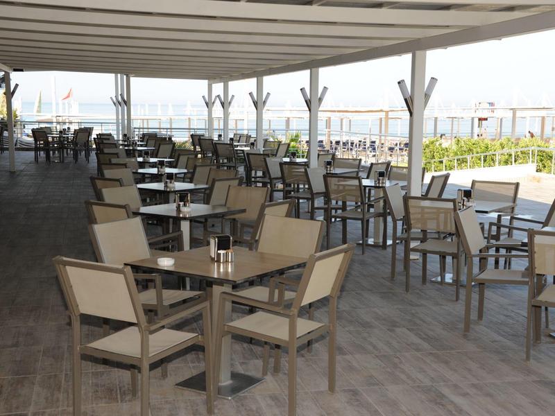 Covered terrace with multiple tables and chairs overlooking water.