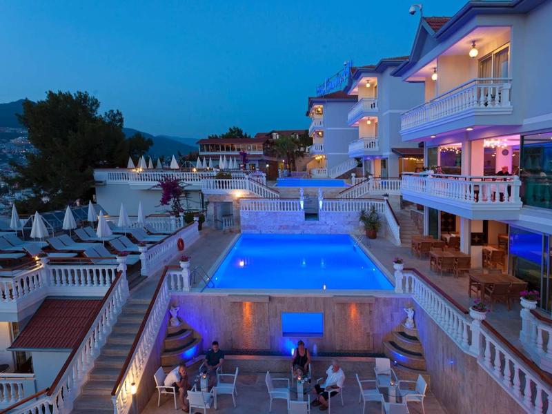 Hotel s osvětleným bazénem a posezením za soumraku, klidná dovolená atmosféra