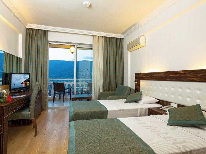 Hotelový pokoj se dvěma postelemi, balkonem s výhledem na hory a dřevěnou podlahou