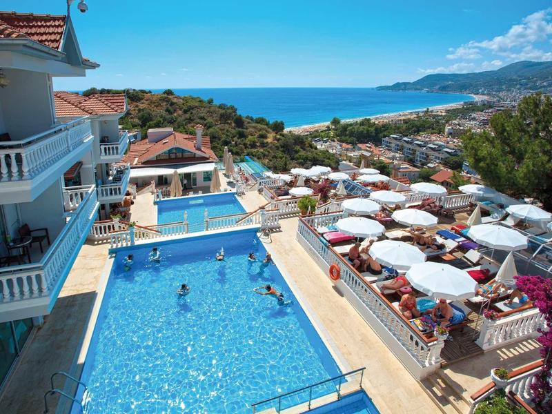 Hotel se dvěma bazény, slunečními parasoly a výhledem na moře.