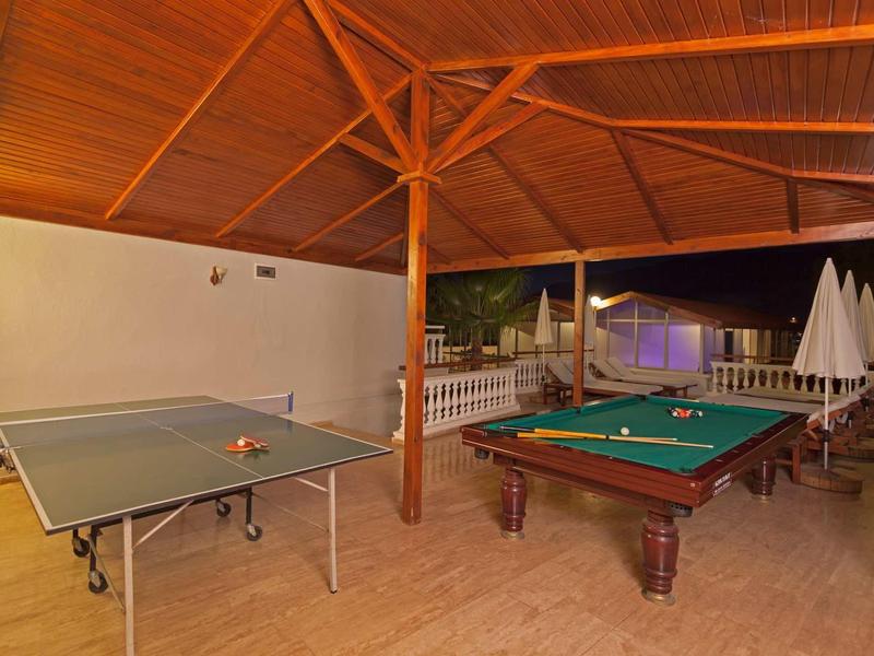 Zastřešená rekreační plocha s pingpongovým stolem a kulečníkovým stolem na dlažbě.