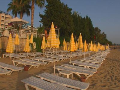 Fila di lettini vuoti con ombrelloni gialli chiusi sulla spiaggia sabbiosa al tramonto.