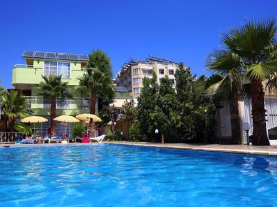 Lichtgroen hotel met blauw zwembad en palmbomen onder een heldere blauwe lucht