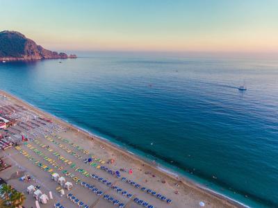 Blick auf einen breiten Sandstrand mit bunten Sonnenschirmen und ruhig blauem Meer
