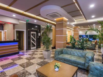 Hall d'hôtel moderne avec canapés confortables, plantes et comptoir de réception élégant.