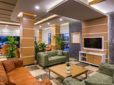 Hall d'hôtel moderne avec canapés confortables, tables et décorée de plantes.