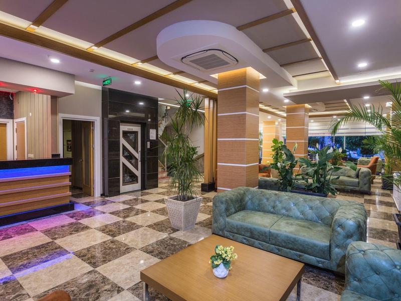 Hall d'hôtel moderne avec canapés confortables, plantes et comptoir de réception élégant.