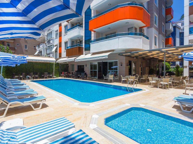 Espace piscine extérieur moderne avec chaises longues et parasols bleus dans un hôtel.