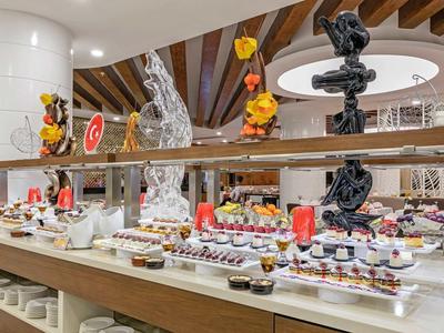 Großes Buffet mit vielfältigen Desserts, moderner Einrichtung und Holz-Elementen im Restaurant.