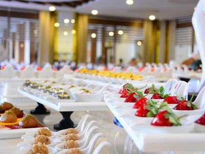 Buffet mit verschiedenen Desserts auf weißen Tellern, dekoriert mit frischen Erdbeeren und Sahne.