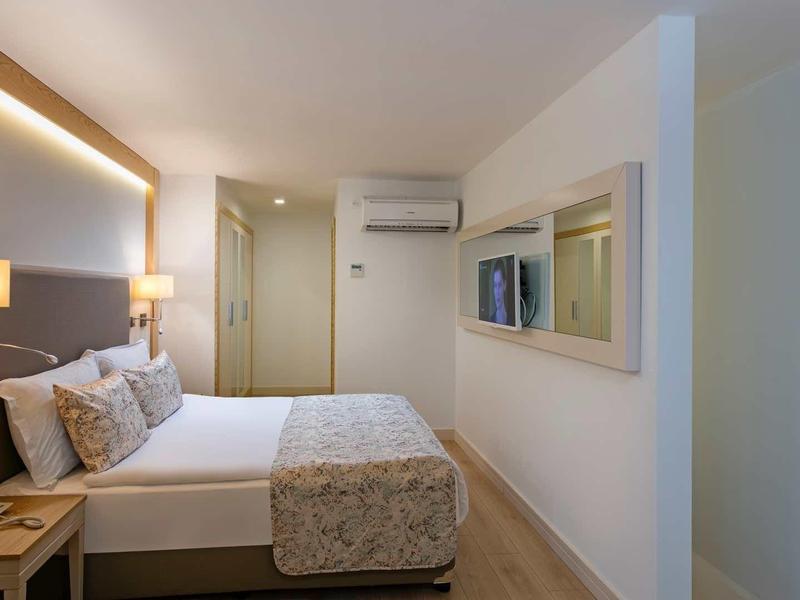 Modern hotel room with large bed, wall lighting, and air conditioning.