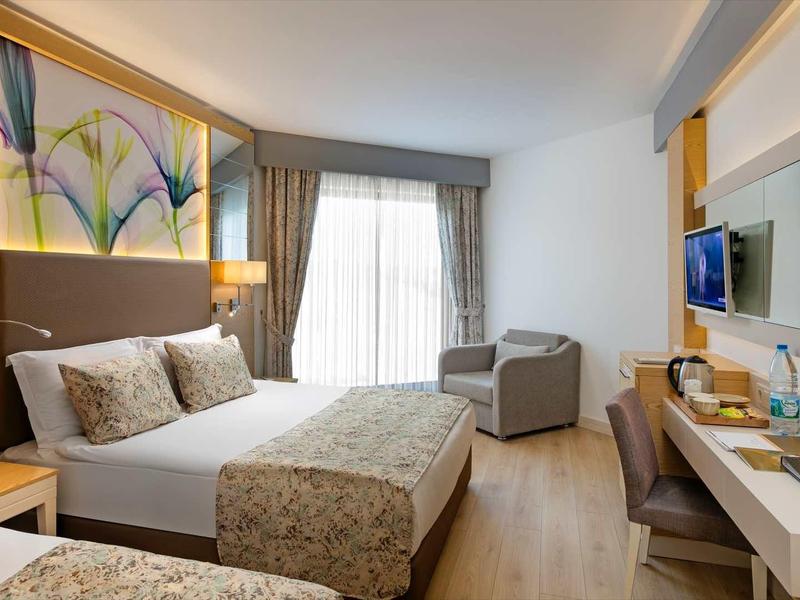 Modern hotel room with double bed, desk, and armchair by the window