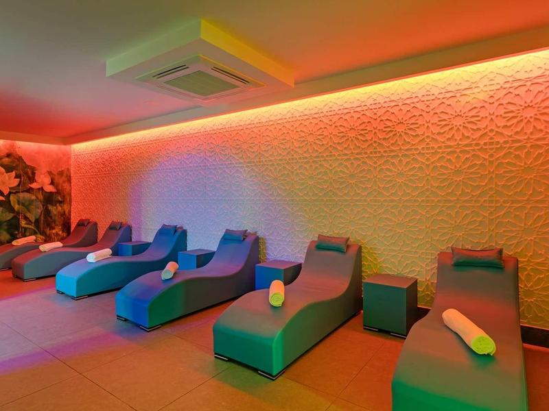 Relaxation room with blue loungers, warm lighting, and decorative wall design.