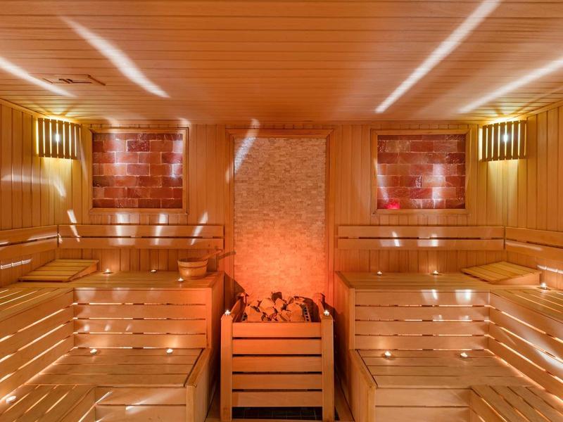 Wood sauna with multi-level benches and central stone heater with red lighting