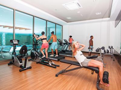 Interno di una palestra con più persone che usano attrezzi per allenarsi.