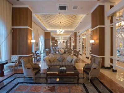 Eleganter, weitläufiger Hotel-Lobby mit bequemen Sitzecken, warmem Holz und großem Kronleuchter.