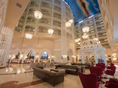 Großer, eleganter Hotellobby mit Kronleuchtern, hohen Fenstern, Sitzgruppen und bemaltem Himmel.