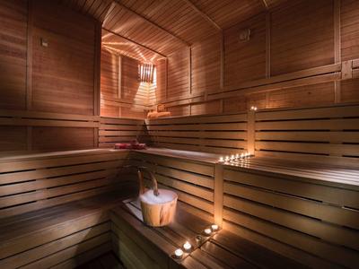 Holzsauna mit hölzernen Bänken, Eimer und Kerzen für stimmungsvolle Beleuchtung.