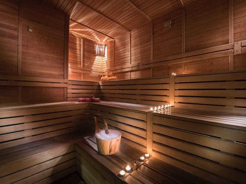 Holzsauna mit hölzernen Bänken, Eimer und Kerzen für stimmungsvolle Beleuchtung.