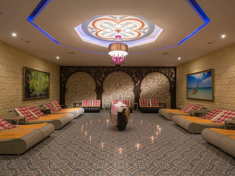 Großer Raum mit bequemen Sofas, orientalischem Muster an Wänden und Decke, warmes Licht, Teppichboden.