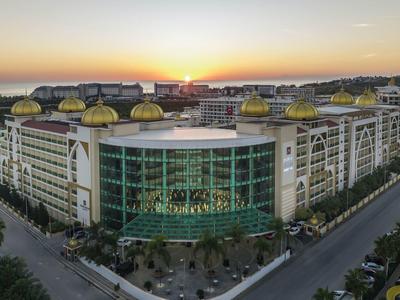 Velká moderní hotelová budova se zlatými kopulemi za západu slunce.