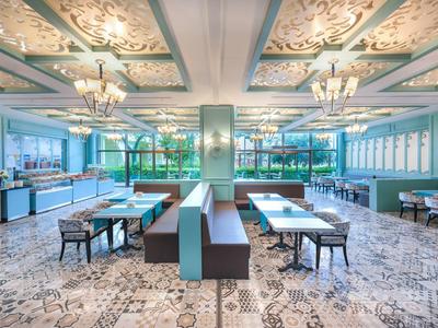 Světá, moderní restaurace s geometrickými dlaždicemi na podlaze a modrošedými lavicemi.