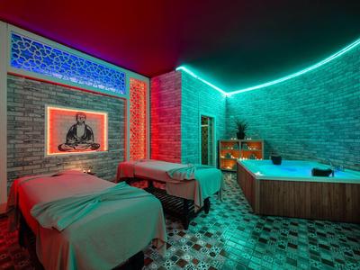 Hotelový pokoj se dvěma postelemi, vířivkou a atmosférickým barevným osvětlením.