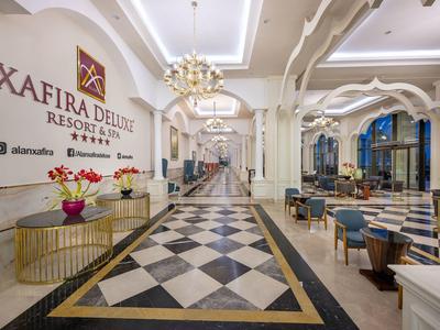 Elegantní hotelová hala s černo-bílou šachovnicovou podlahou a stylovými posezeními.