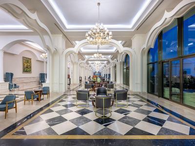 Elegante Hotellobby mit schwarz-weiß kariertem Boden, Kronleuchtern und großen Fenstern.