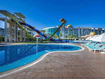 Toboganes acuáticos y una gran piscina en un resort hotelero bajo un cielo despejado.