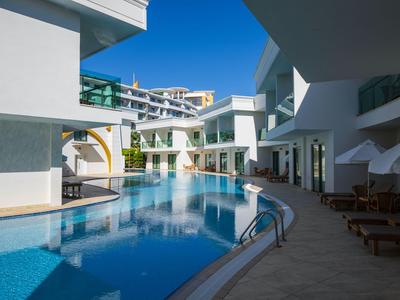 Piscina moderna de hotel con tumbonas y agua azul clara bajo un cielo soleado.