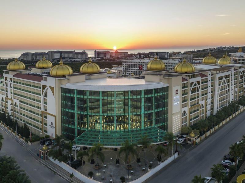 Velká moderní hotelová budova se zlatými kopulemi za západu slunce.