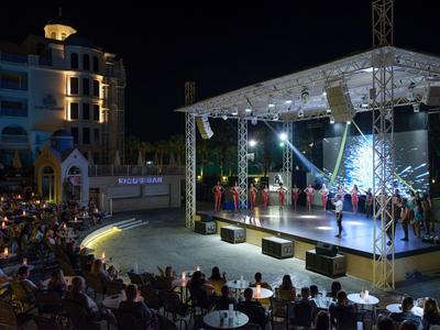 Palco illuminato con spettacolo di danza davanti al pubblico di notte in hotel o area eventi.