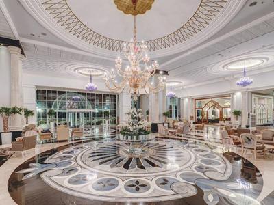 Luxueux hall d'hôtel avec sol en marbre, lustre élégant et sièges confortables.