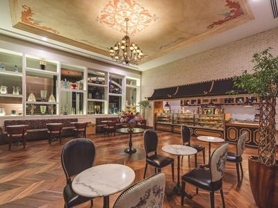 Salon élégant avec tables en marbre, chaises noires et buffet dans un cadre classique.