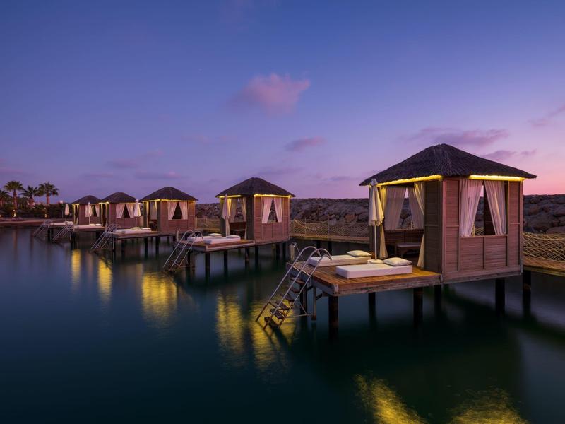 Cabanes sur pilotis éclairées au crépuscule au-dessus de l'eau calme.