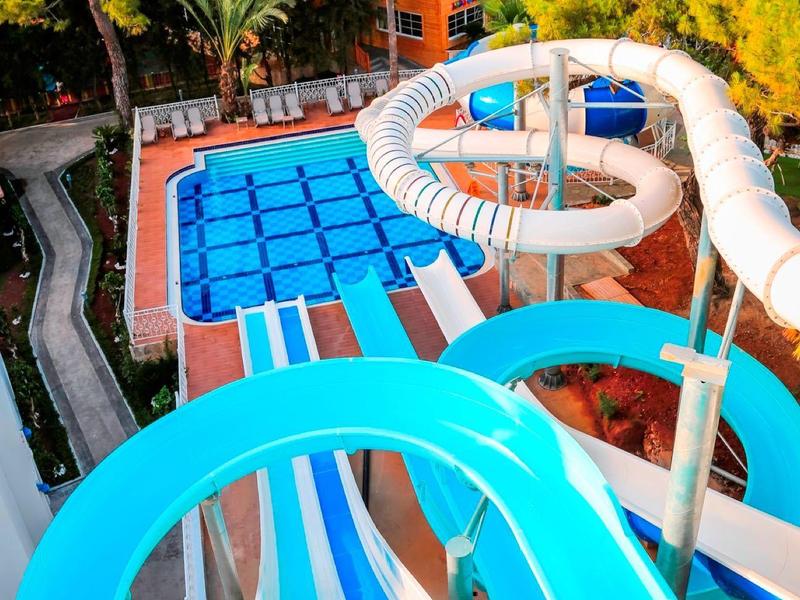Toboggans aquatiques bleus dans un parc aquatique entouré de végétation.