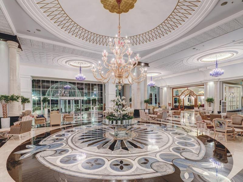 Luxueux hall d'hôtel avec sol en marbre, lustre élégant et sièges confortables.