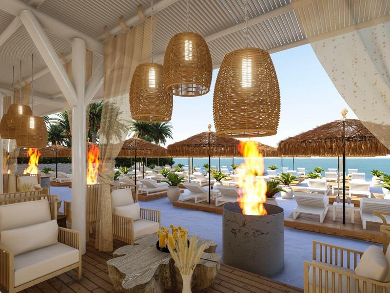 Terrasse d'hôtel élégante avec sièges confortables, lampes suspendues et vue sur piscine et mer.