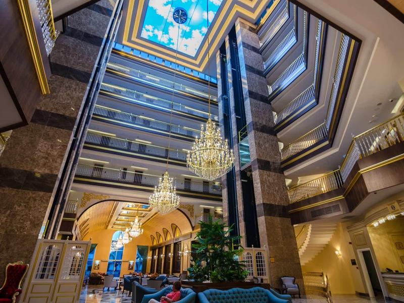 Luxusní hotelová hala s lustry, vícepodlažním atriem a elegantním zařízením.